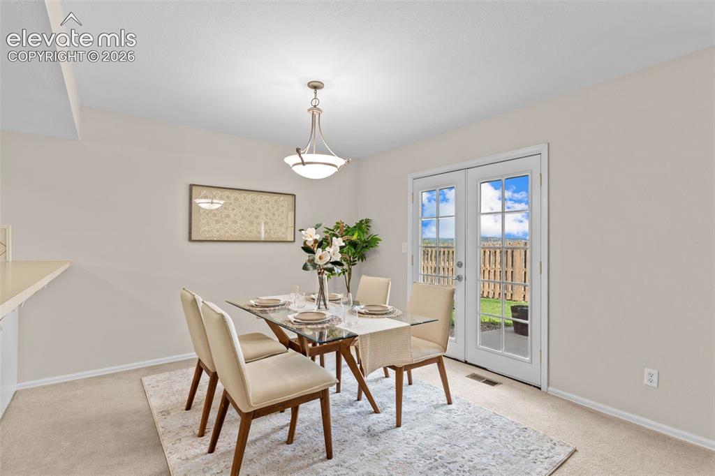 Image 9 of 32: Bright dining area featuring a glass-top table, overhead pendant lighting, 