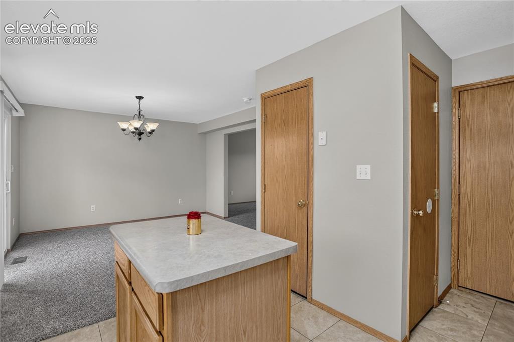 Image 16 of 36: Kitchen island with light-toned countertop, wood cabinetry, and tiled floor