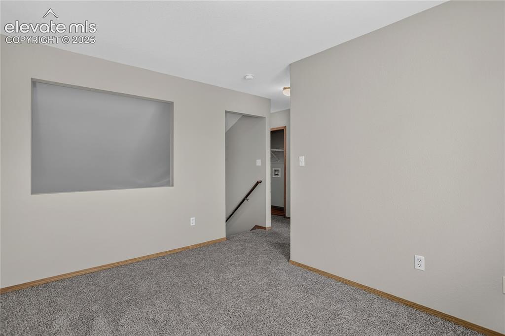 Image 20 of 36: Gray carpeting, light-toned walls, and wood-finish trim