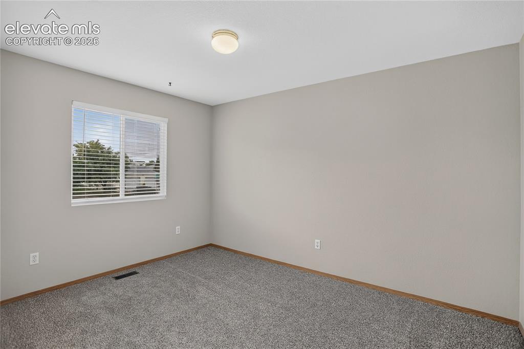 Image 23 of 36: Wall-to-wall carpeting, neutral wall color, and a window with horizontal bl