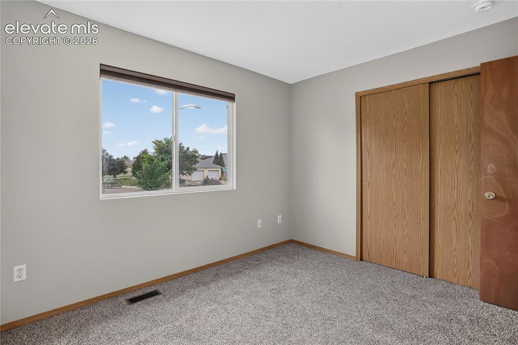 Image 24 of 36: Carpeted flooring, window with blinds, sliding closet doors with wood-finis