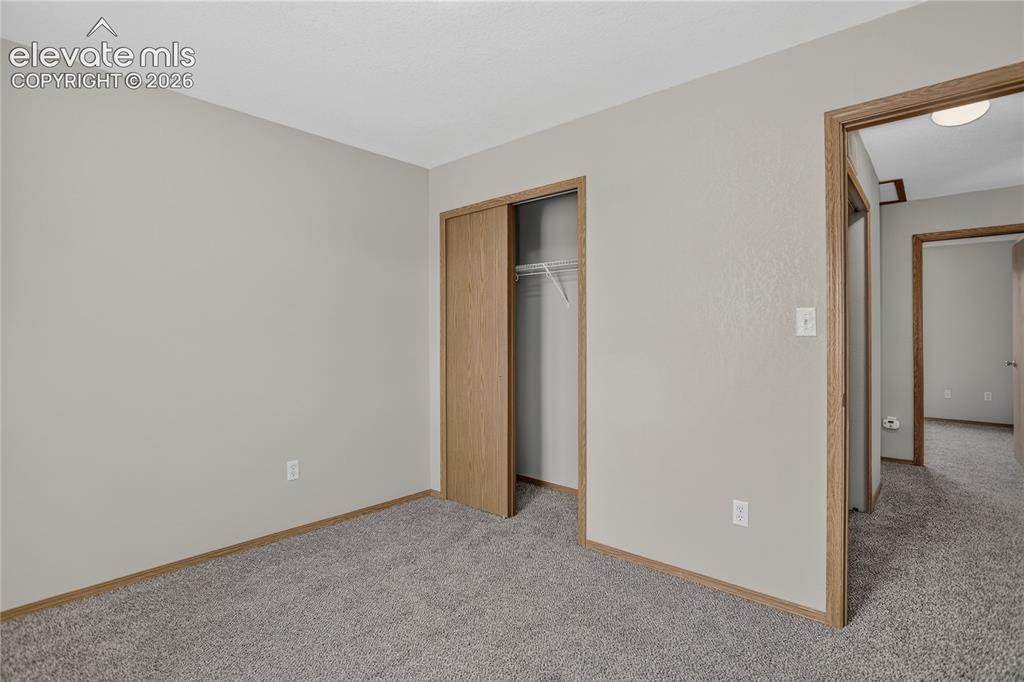 Image 28 of 36: Neutral wall paint and trim, gray carpet flooring, wood-finish closet doors