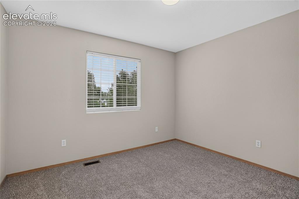 Image 29 of 36: Neutral-toned walls, plush carpet flooring, window with horizontal blinds,