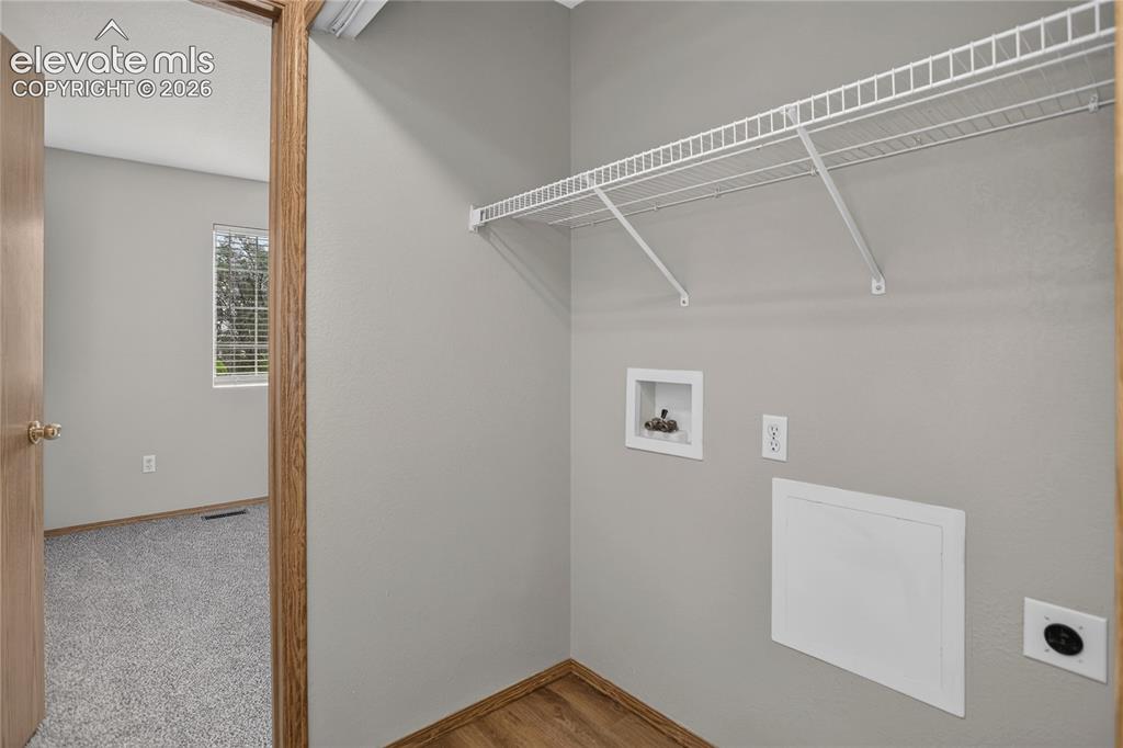 Image 30 of 36: Utility area with wood-finish flooring, wire shelving, and appliance hookup