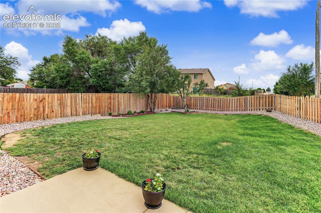 Image 32 of 36: Expansive backyard featuring a large grass area, wood privacy fencing, and