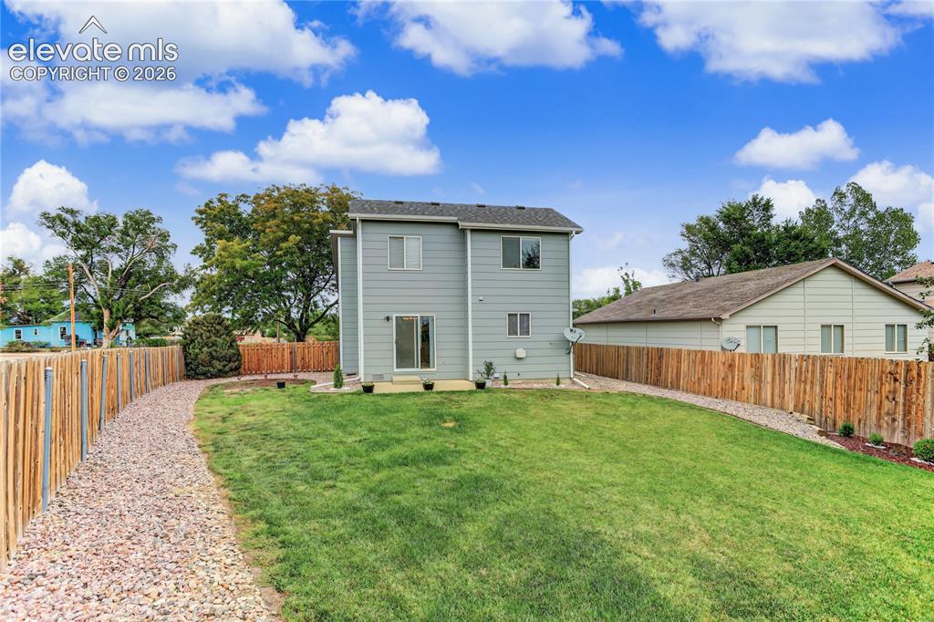 Image 35 of 36: Expansive backyard featuring a manicured lawn, a gravel path, and wood fenc