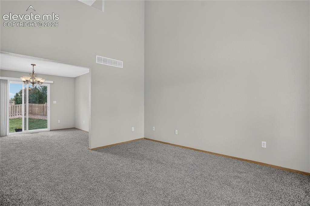 Image 5 of 36: Vaulted ceilings, neutral wall tones, gray carpeting, wood-finish trim, and