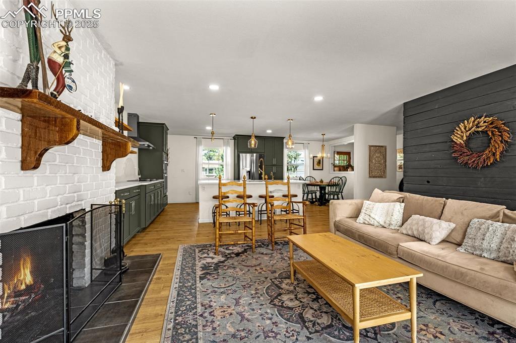 Image 12 of 43: Living room with wood walls, a brick fireplace, light wood-style floors, re