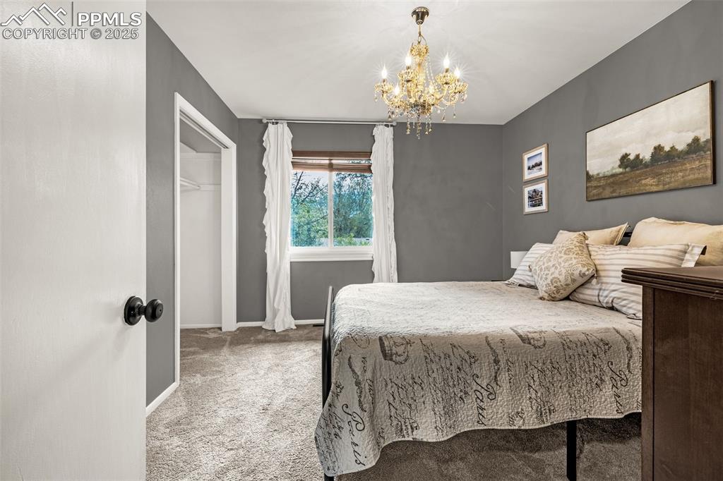 Image 25 of 43: Bedroom featuring light colored carpet and a chandelier