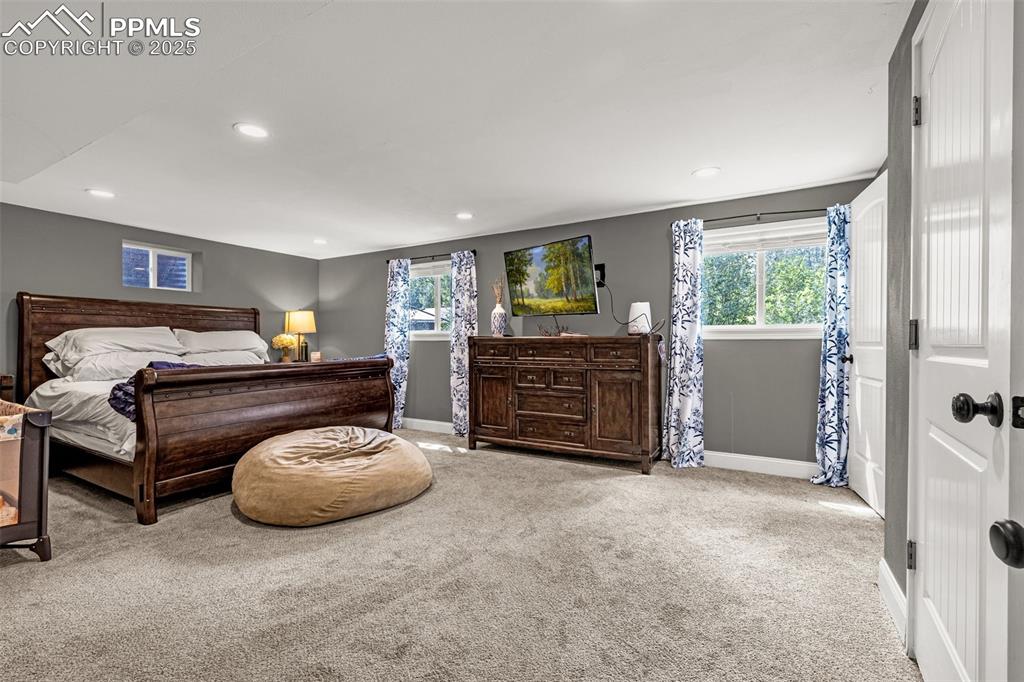 Image 26 of 43: Bedroom with light carpet, multiple windows, and recessed lighting