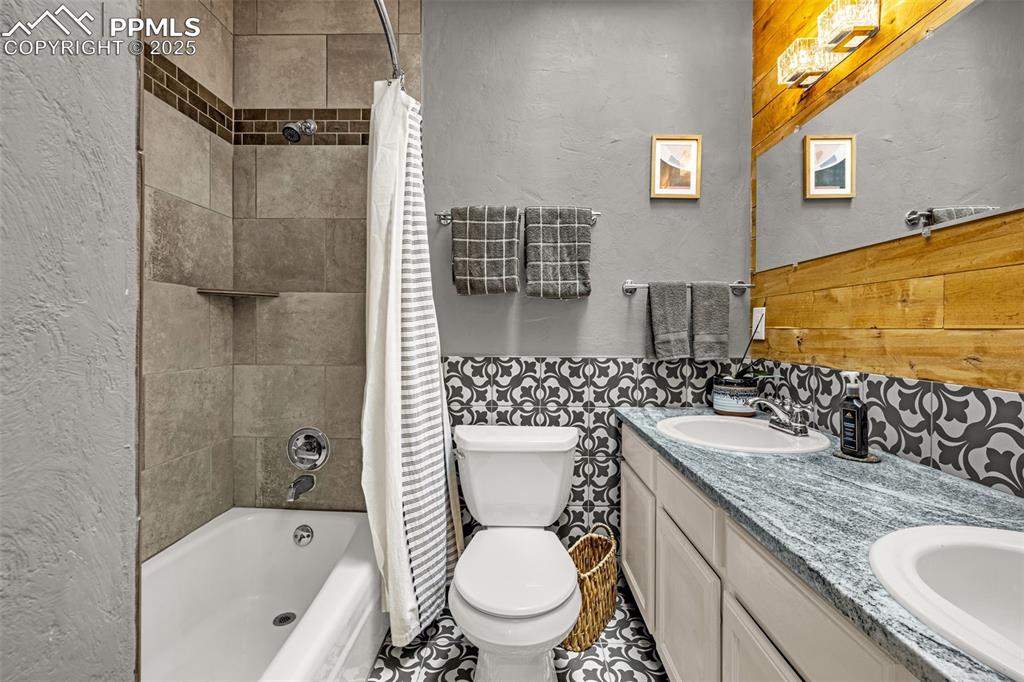 Image 29 of 43: Full bath with a textured wall, shower / bath combo, double vanity, wainsco