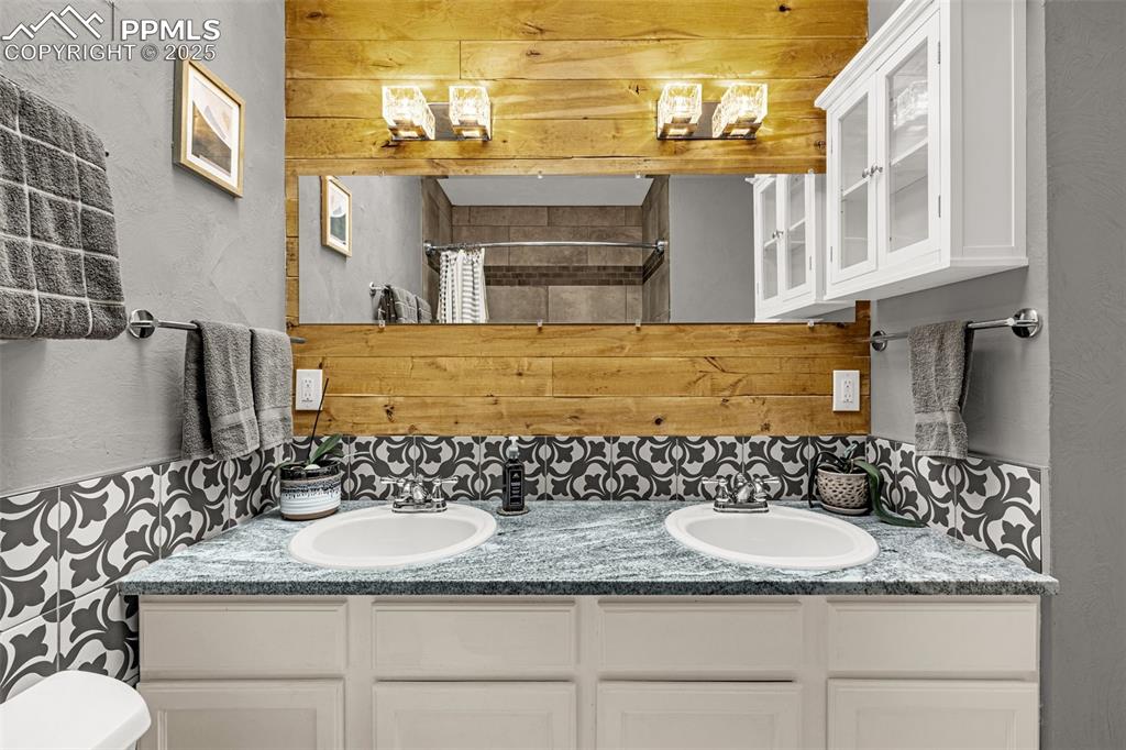 Image 30 of 43: Bathroom featuring a textured wall, double vanity, a shower with curtain, w