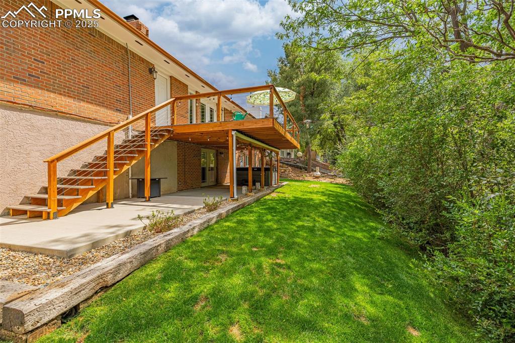 Image 35 of 43: View of grassy yard with a patio area, stairway, and a deck