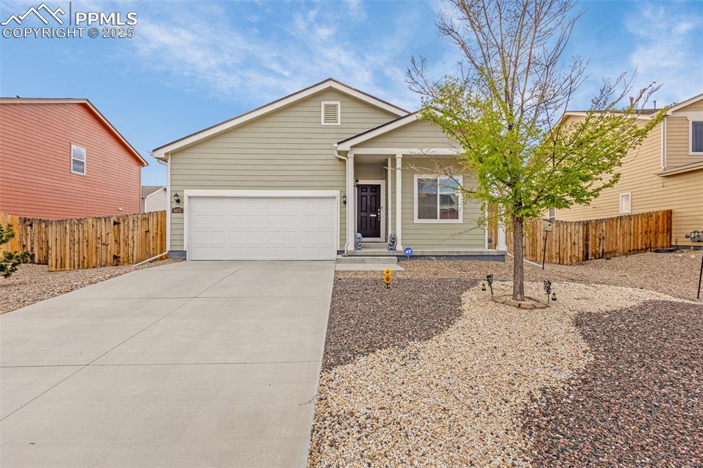 Caption: View of front facade featuring concrete driveway, an attached garage, and fence