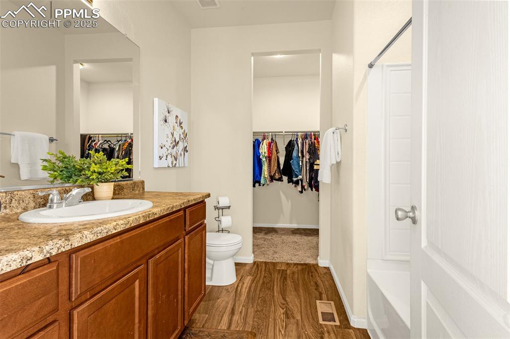 Image 15 of 28: Bathroom featuring a spacious closet, wood finished floors, visible vents, 