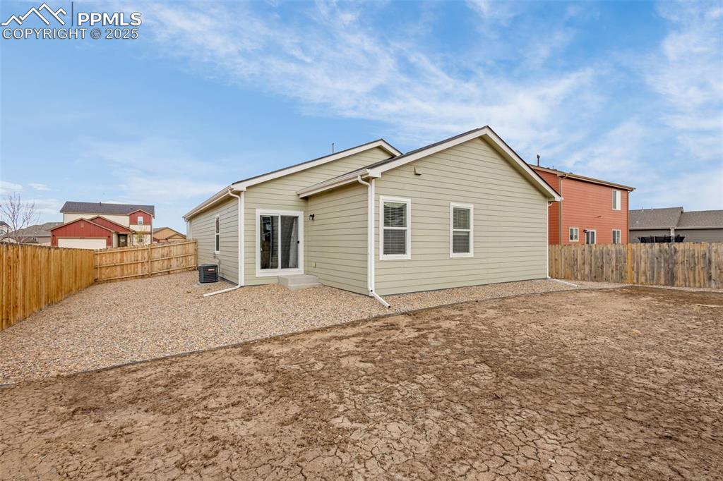 Image 20 of 28: Rear view of house featuring central air condition unit and a fenced backya