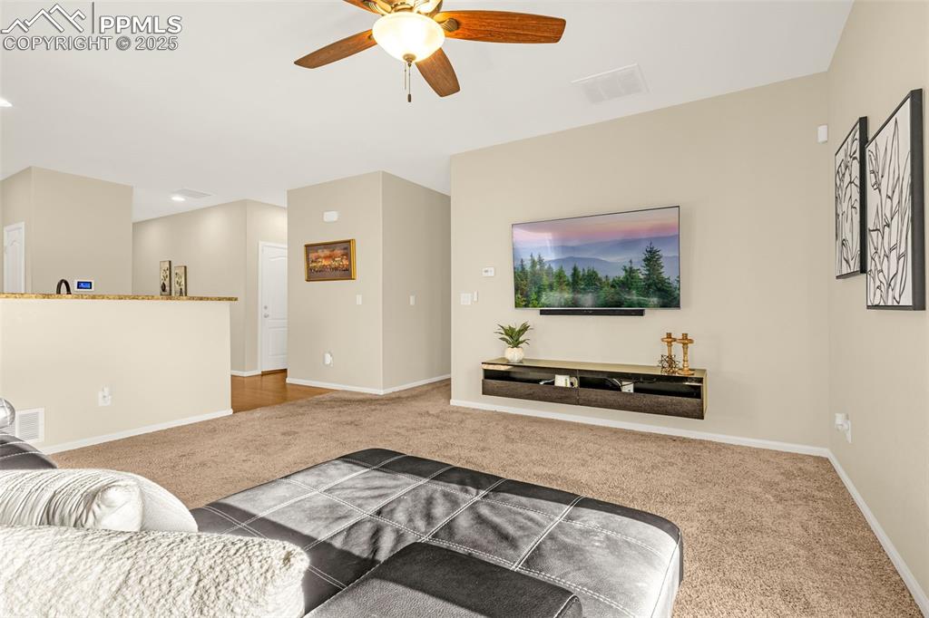 Image 5 of 28: Carpeted living room with baseboards, a ceiling fan, and visible vents