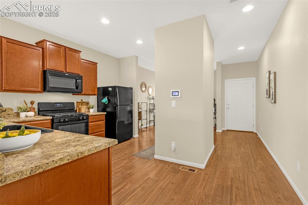 Image 6 of 28: Kitchen featuring brown cabinets, light wood finished floors, light counter