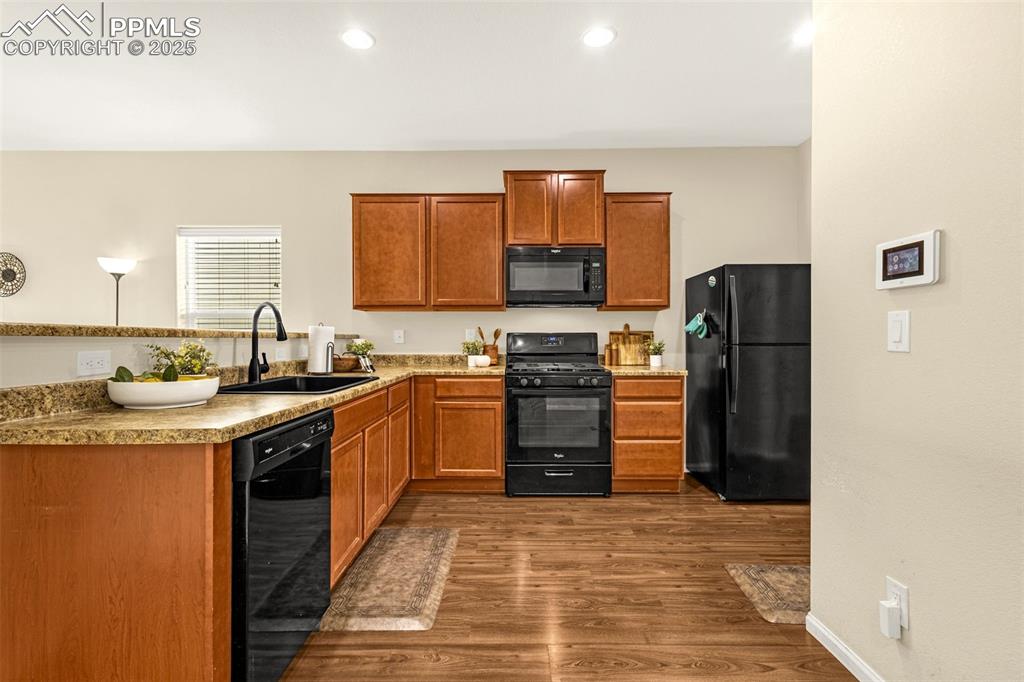 Image 7 of 28: Kitchen with recessed lighting, a sink, black appliances, brown cabinetry, 