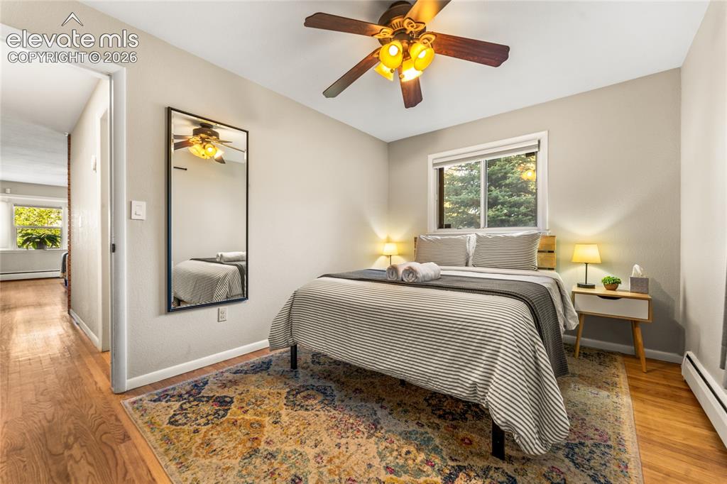 Image 13 of 39: Bedroom with light wood finished floors, multiple windows, and a baseboard