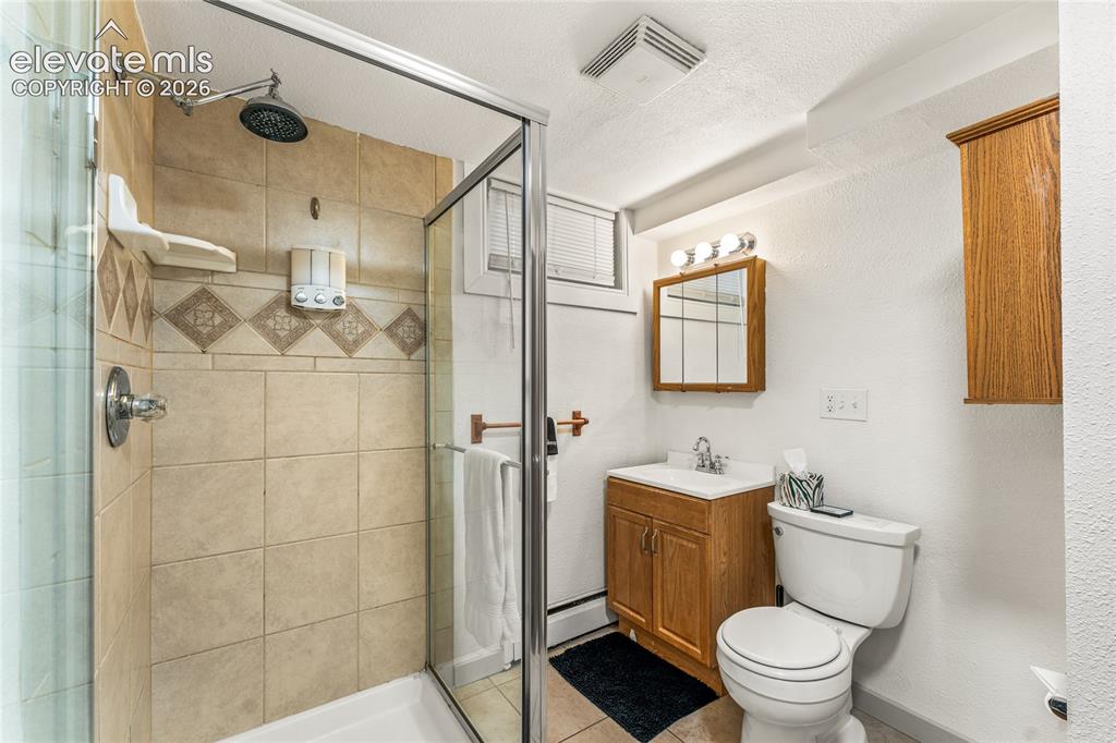 Image 19 of 39: Full bathroom featuring a shower stall, light tile patterned floors, vanity