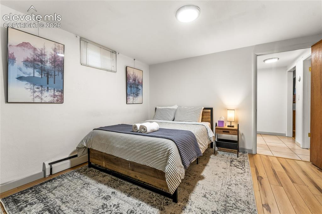 Image 22 of 39: Bedroom with wood finished floors and baseboard heating