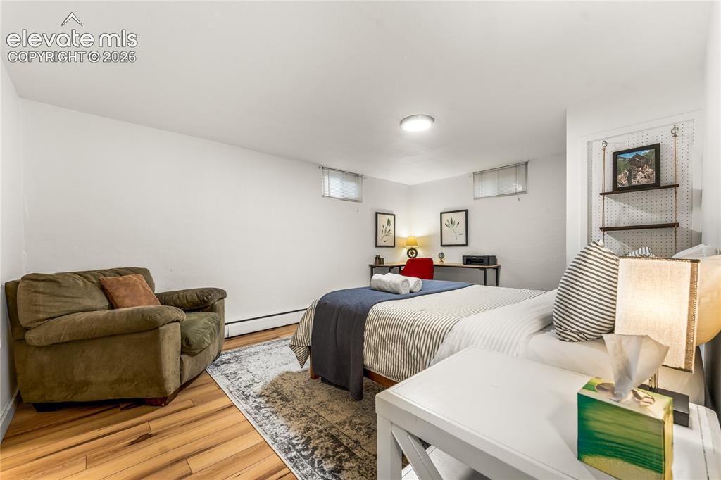 Image 24 of 39: Bedroom with wood finished floors and baseboard heating