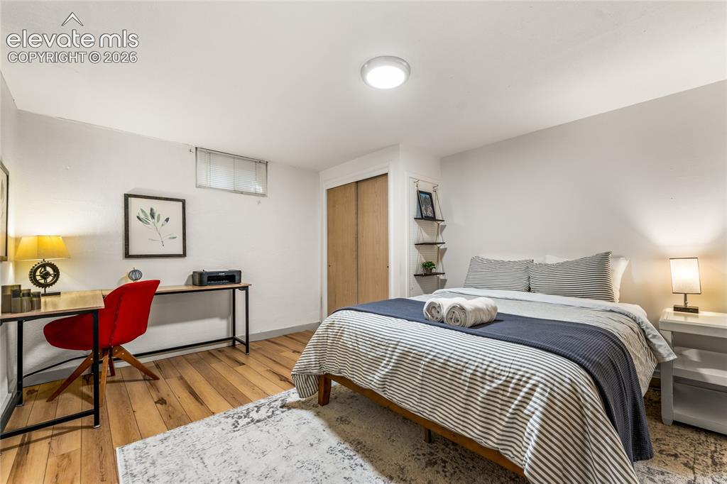 Image 25 of 39: Bedroom with a closet, light wood-style floors, and an office area