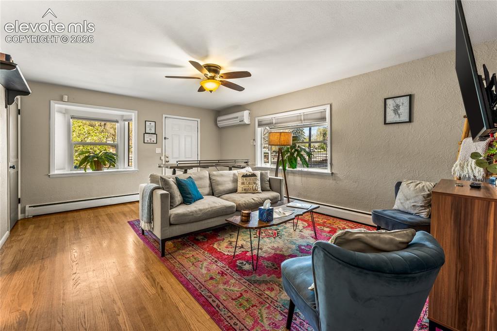 Image 3 of 39: Living area featuring a textured wall, wood finished floors, a baseboard he