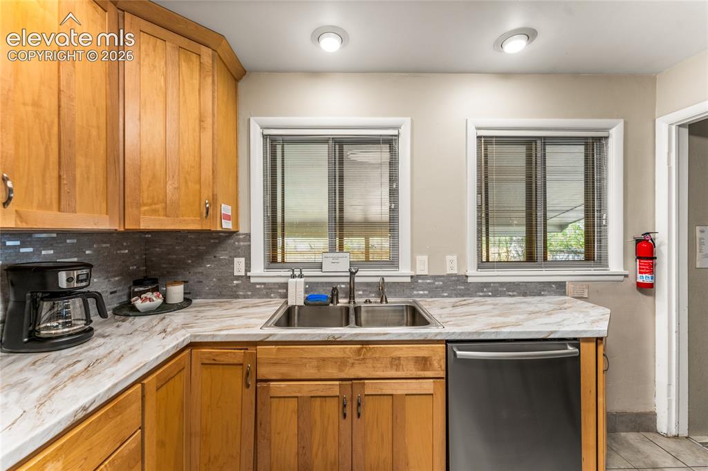 Image 9 of 39: Kitchen featuring light countertops, backsplash, stainless steel dishwasher