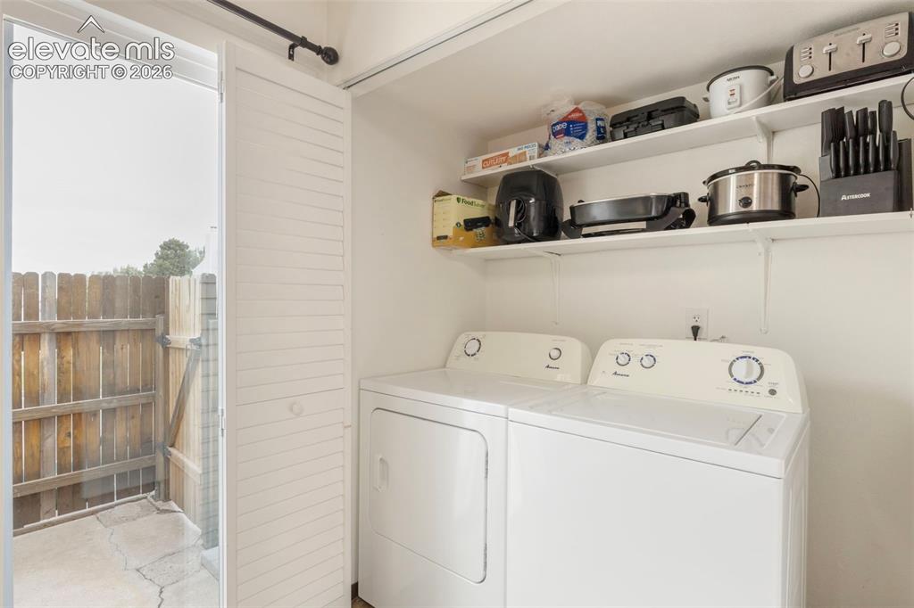 Image 12 of 26: Dedicated laundry area featuring a white washer and dryer, integrated shelv
