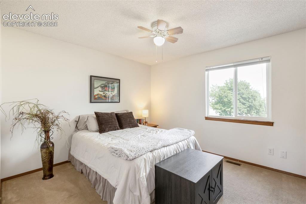 Image 15 of 26: Bedroom featuring a ceiling fan, a large window with a wood-finish sill, an