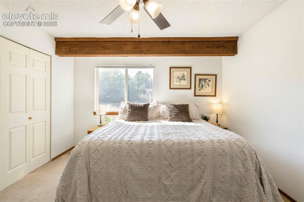 Image 19 of 26: Bedroom featuring a decorative wood beam, dual-pane window, and textured ce
