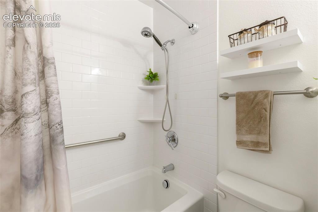 Image 20 of 26: Bathroom featuring a white subway tile surround, built-in tub with shower,