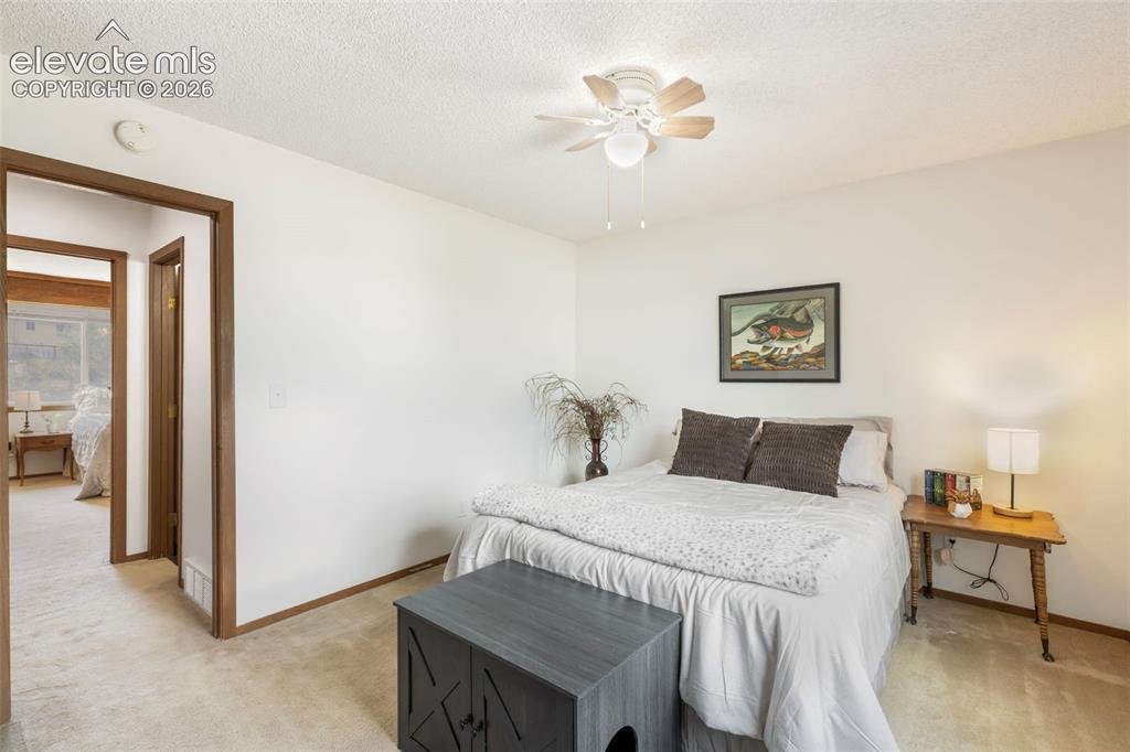 Image 22 of 26: Carpeted room with a ceiling fan light fixture, white walls, and wood trim
