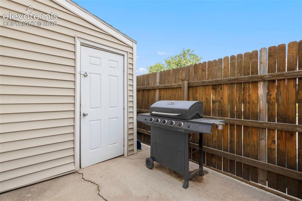 Image 25 of 26: Fenced patio area with storage shed and access to crawl space