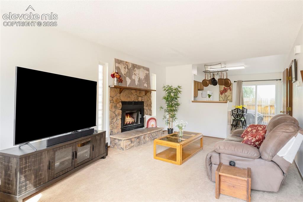 Image 3 of 26: Living room featuring a stone-clad fireplace with a hearth, light neutral c