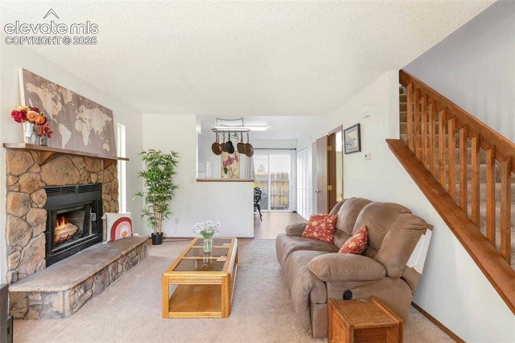 Image 4 of 26: Living area with a stone-clad fireplace and hearth