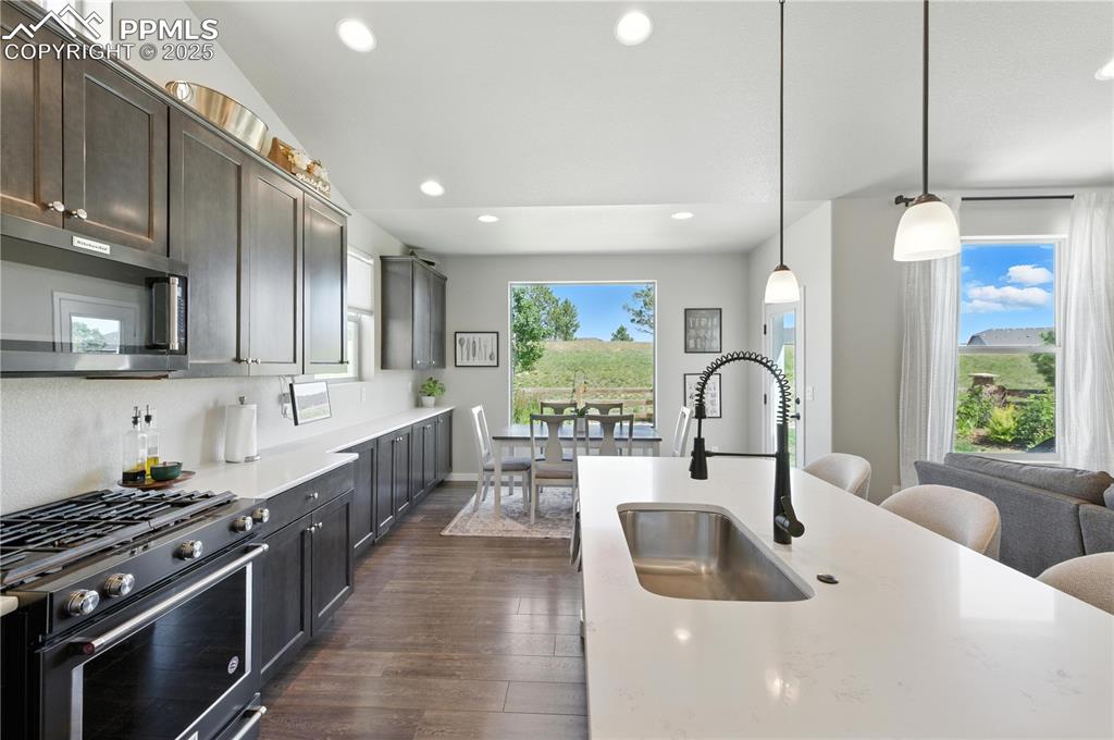 Image 14 of 40: Kitchen with gas range, dark wood-style floors, stainless steel microwave,