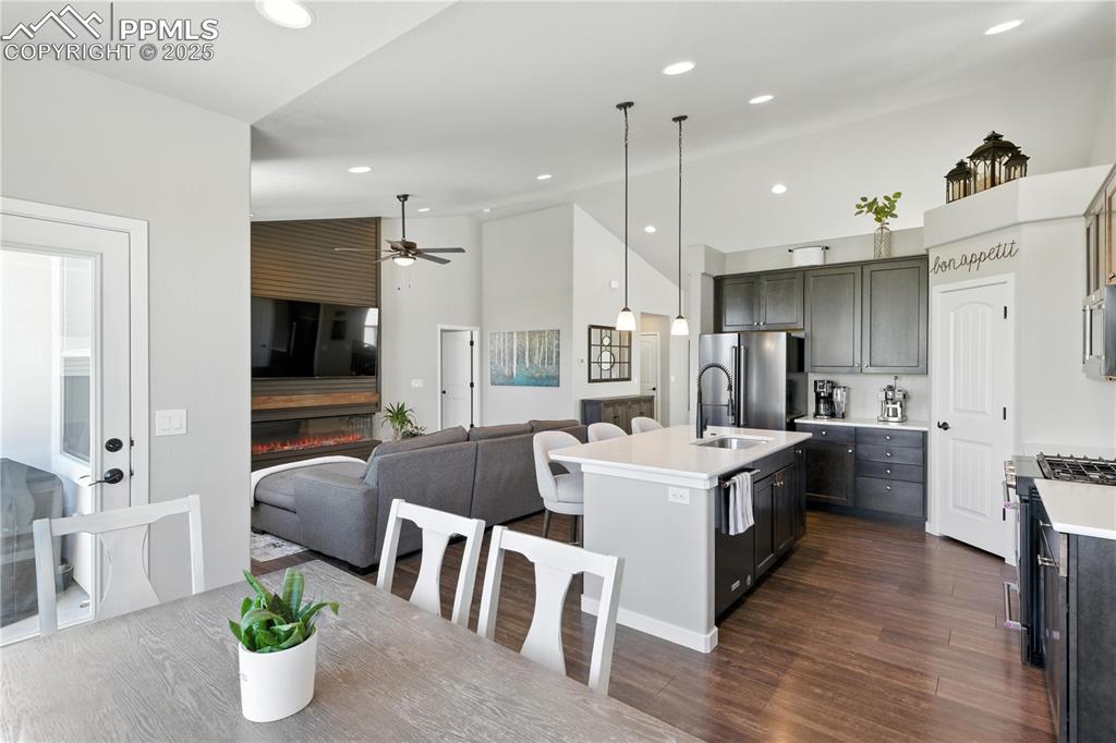 Image 15 of 40: Kitchen with open floor plan, an island with sink, light countertops, dark