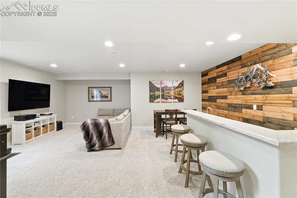 Image 23 of 40: Living room featuring wooden walls, recessed lighting, light carpet, and ba