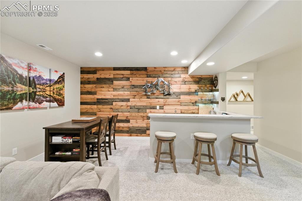 Image 25 of 40: Indoor dry bar featuring wooden walls, recessed lighting, light colored car