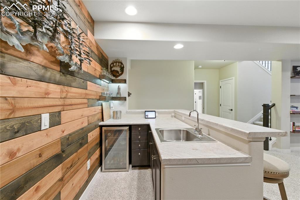 Image 27 of 40: Kitchen featuring wine cooler, a breakfast bar area, light countertops, a p