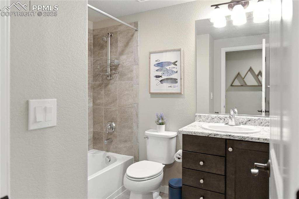 Image 33 of 40: Basement Level Bathroom Full bath with a textured wall, vanity, and bathing