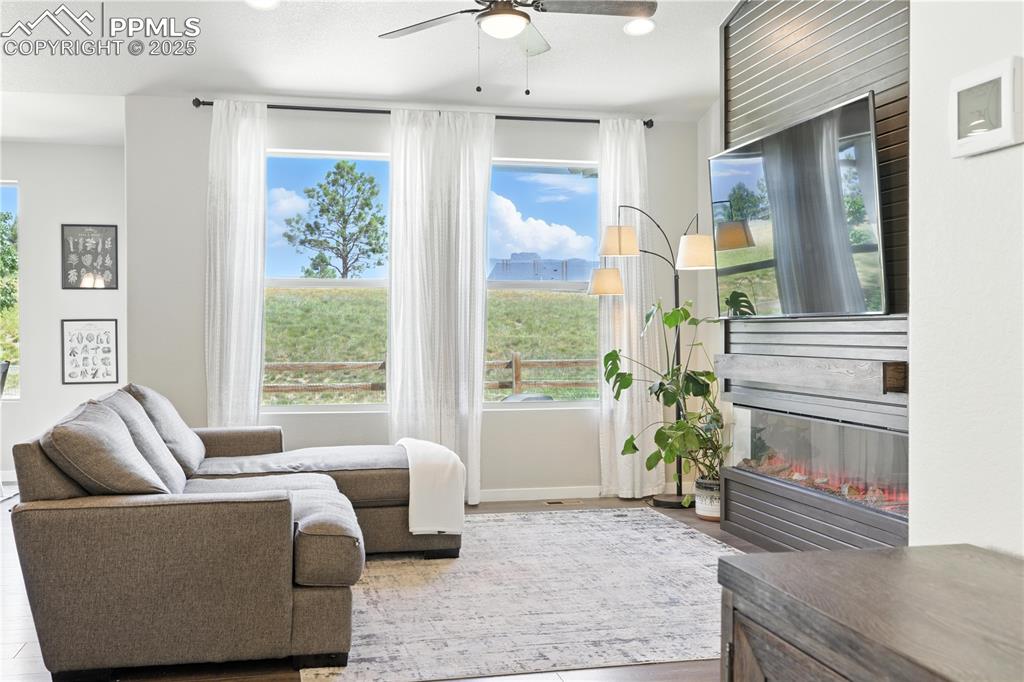 Image 5 of 40: Living area featuring a ceiling fan, a glass covered fireplace, and recesse