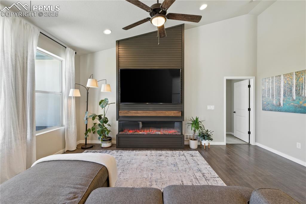 Image 7 of 40: Living room featuring wood finished floors, a ceiling fan, a fireplace, and