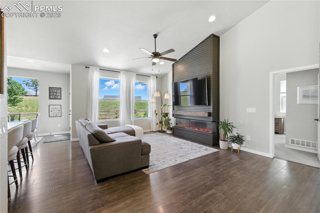 Image 8 of 40: Living room with a fireplace, a ceiling fan, healthy amount of natural ligh