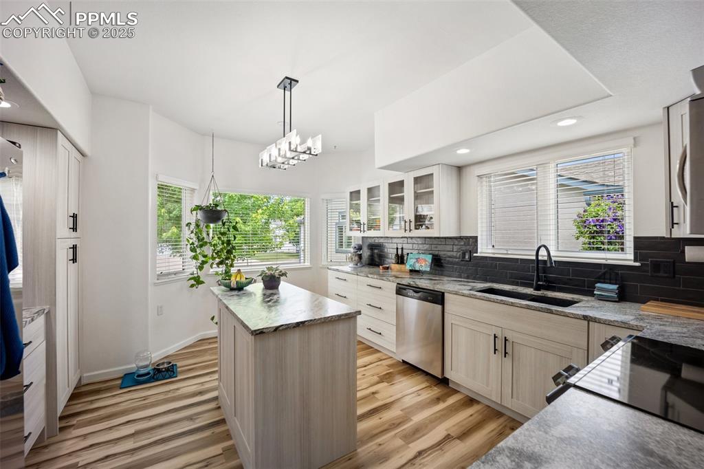 Image 11 of 50: Kitchen with stainless steel dishwasher, light wood-style floors, decorativ