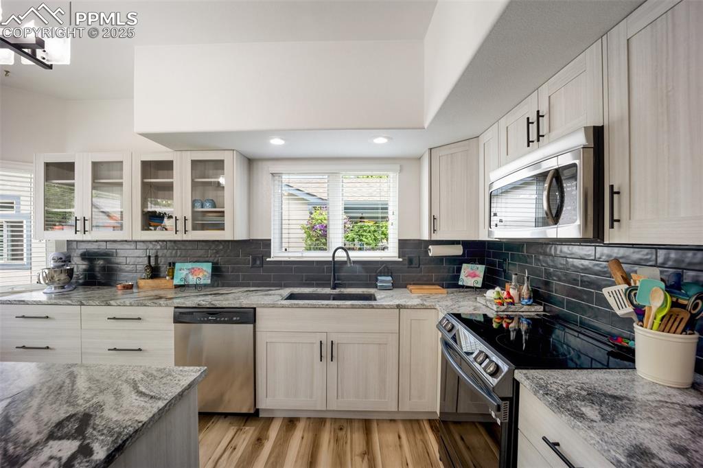 Image 12 of 50: Kitchen with stainless steel appliances, tasteful backsplash, light wood-st