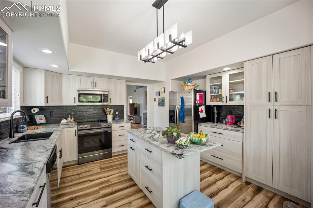Image 14 of 50: Kitchen with appliances with stainless steel finishes, backsplash, light wo